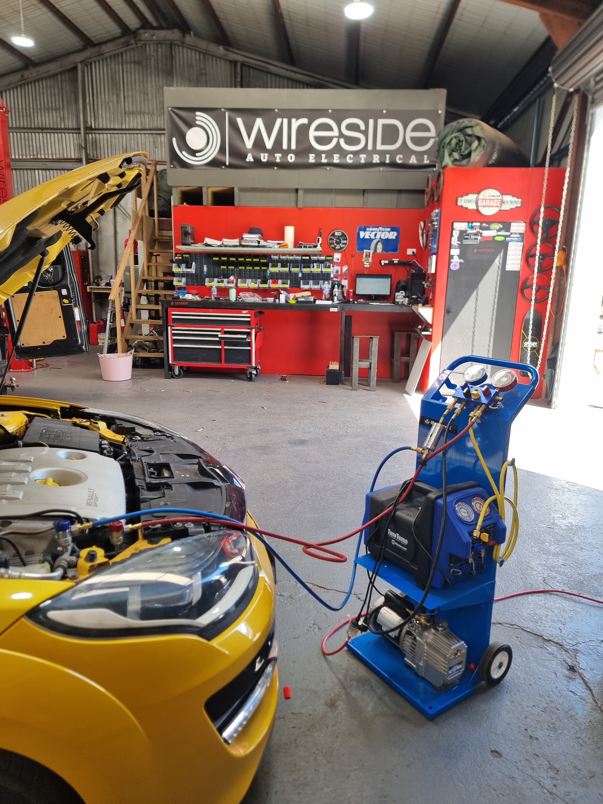 A yellow Renault Sport hatch hooked up to an air conditioning service machine in the Wireside workshop