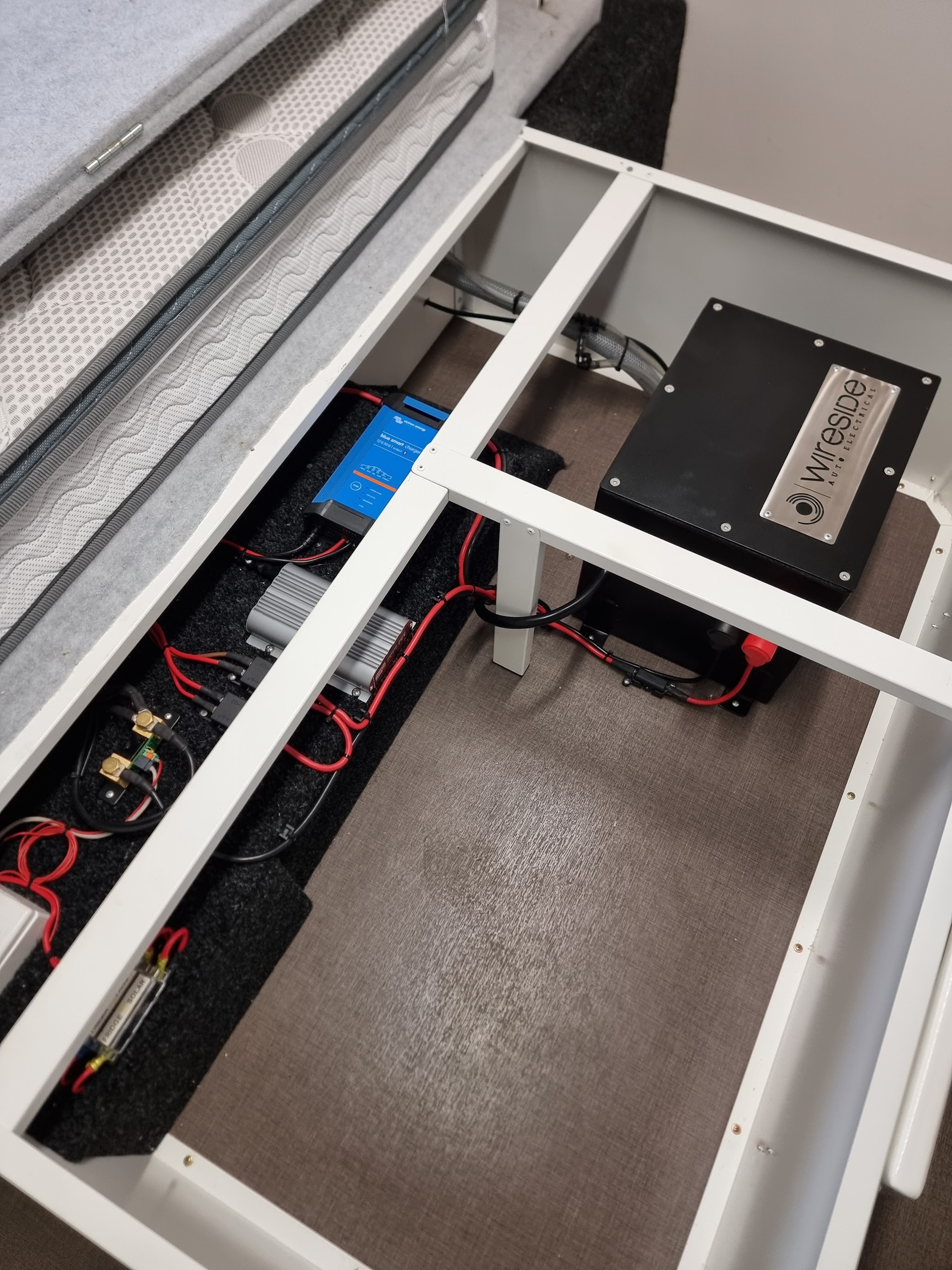 Under-bed caravan electrical fitout with a Victron charger and a Wireside-plated battery box