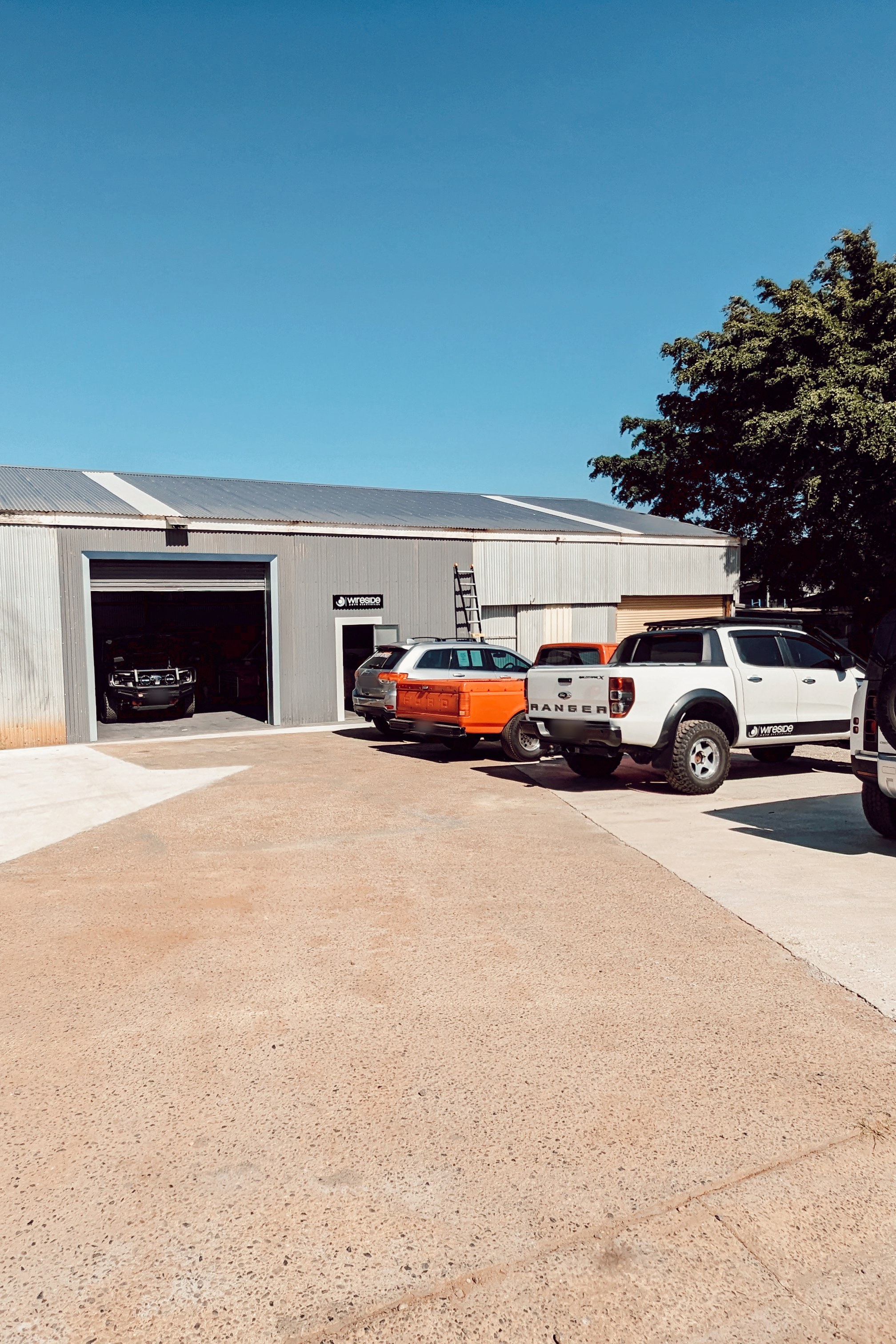 The Wireside Auto Electrical shed on John Oxley Drive, roller door open, with a Wireside-branded Ford Ranger out front